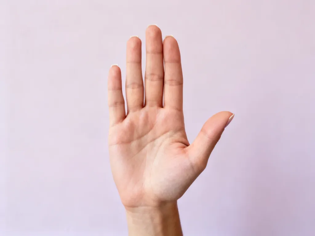 Dłoń wykonująca gest „stop”, symbolizująca stanowczą odmowę w nowoczesnym, minimalistycznym stylu.